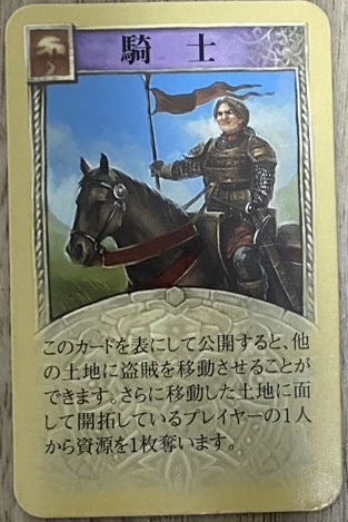 実際のカタンの発展カード「騎士」を撮影した写真。表にすると盗賊を移動させ、隣接するプレイヤーから資源を1枚奪える効果が書かれている